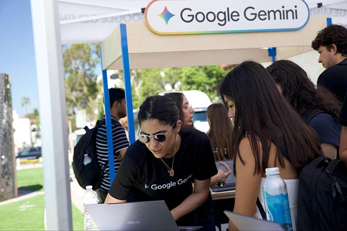 A Google Gemini team member explains features of the AI tool to students gathered at an outdoor demonstration booth on campus.